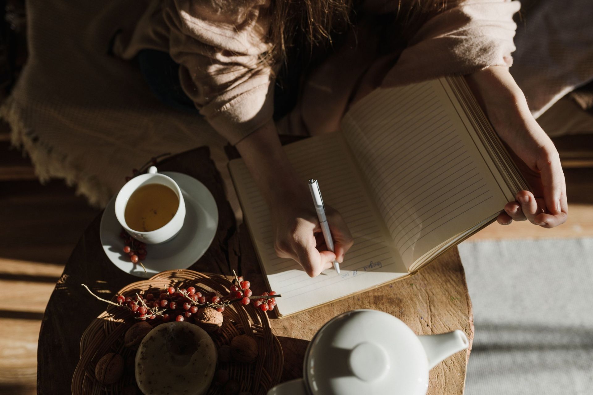A woman writing in a journal with a cup of tea